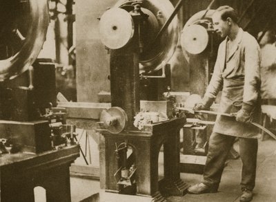 Money making-cutting strips of silver into disks by English Photographer